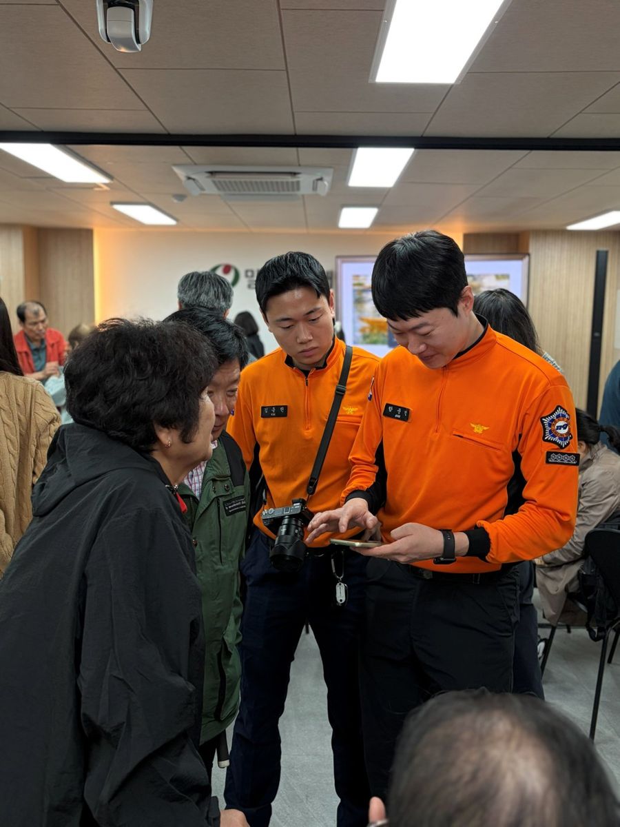 소방관들이 시청각장애인 참가자에게 휴대폰 화면을 보여 주며 안내하고 있다