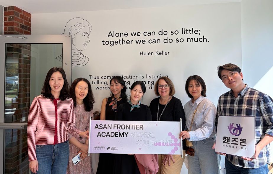 Team members hold a banner in front of a wall with a Helen Keller quote at HKNC